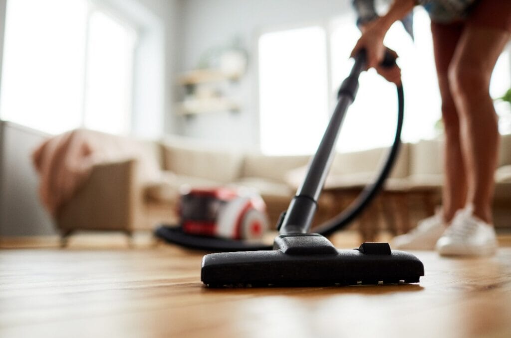 Close-up of unrecognizable woman vacuuming floor at home